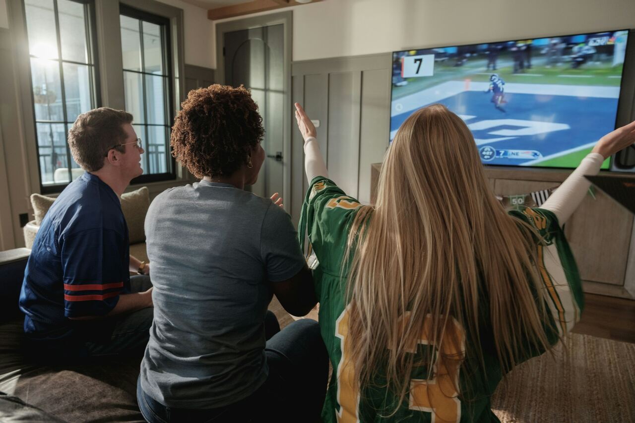 Amigos na sala torcendo enquanto assistem a um jogo de futebol na TV